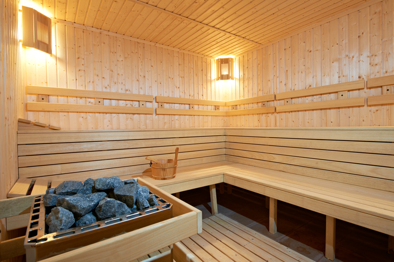 Interior of a traditional sauna with timber cladding, wooden benches and electric sauna heater.